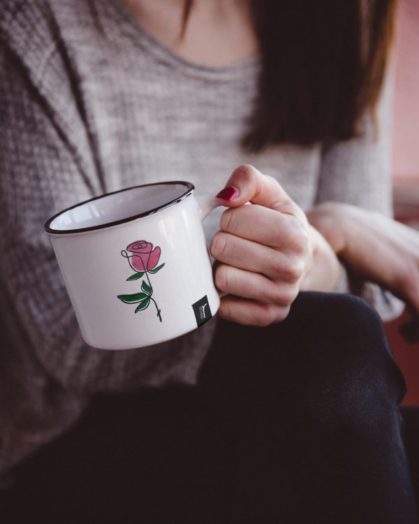 Taza de lata con una flor rosa